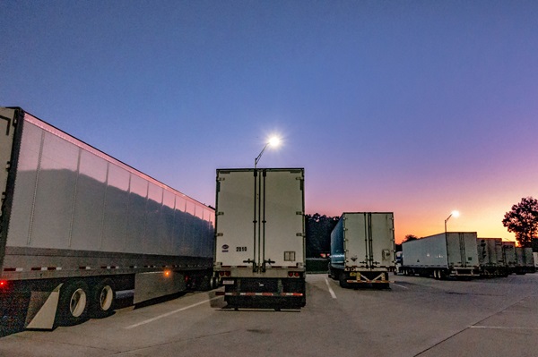 Big rig semi-trucks and tractor-trailers at rest area at sunrise.