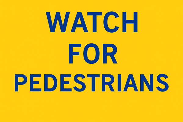 Yellow pedestrian safety sign with bold blue lettering that reads "WATCH FOR PEDESTRIANS."